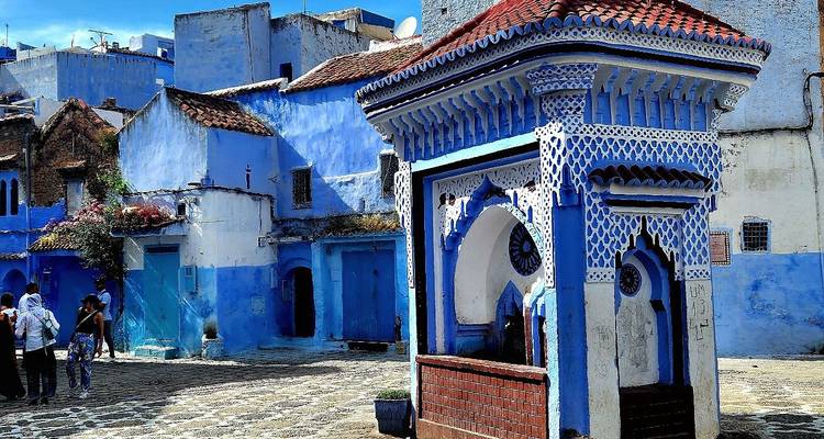Architecture bleue et blanche sur une place de ville marocaine.
