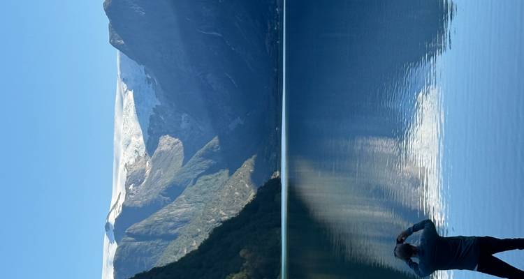 Homme prenant une photo d'un lac avec des montagnes en arrière-plan.