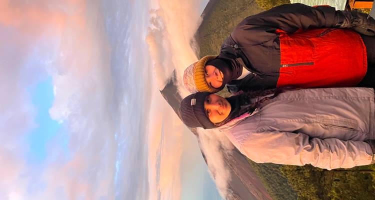 Two people at a high elevation with a volcanic background.