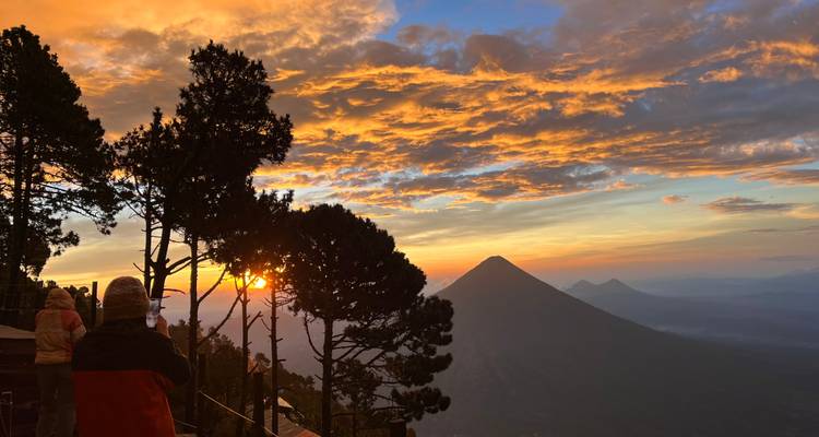 Una persona tomando una foto de un atardecer volcánico.