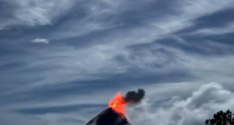 Un volcan en éruption sous un ciel nocturne étoilé.