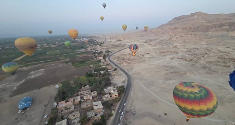 Plusieurs montgolfières au-dessus de champs et d'une route désertique.