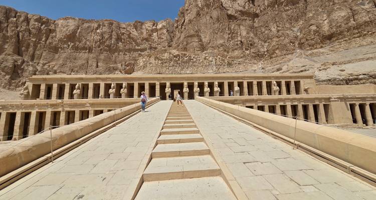 Temple avec colonnes et statues sculptées dans une montagne.