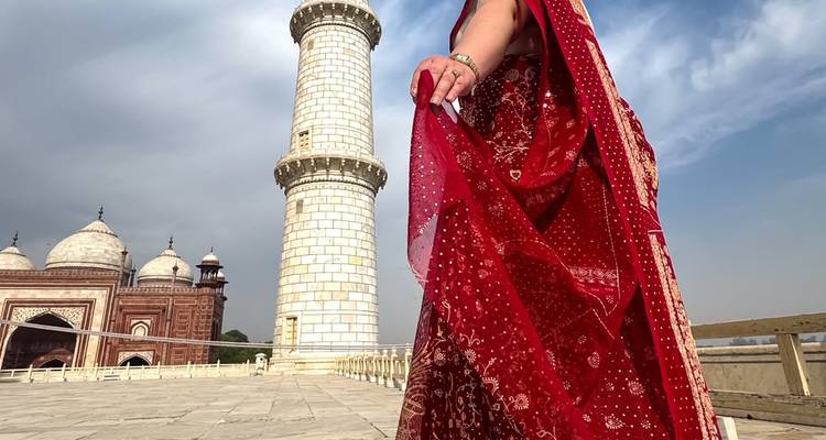 Personne en tenue traditionnelle marchant près d'une tour du Taj Mahal.