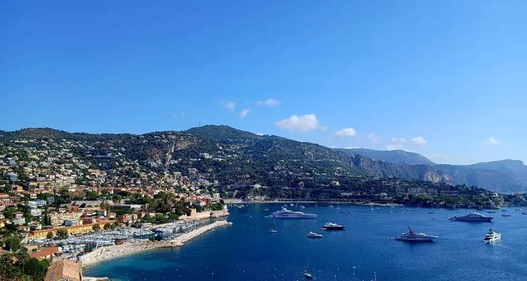 A coastal view with yachts and hillside houses.
