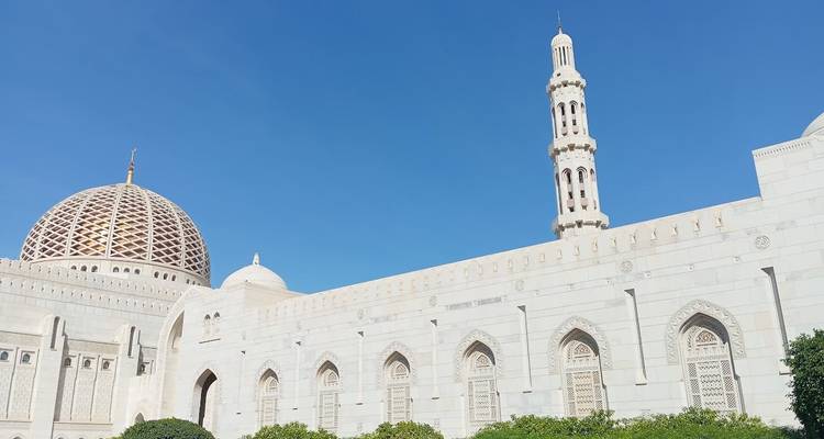 Une grande mosquée avec un grand dôme et un minaret sous un ciel bleu clair.