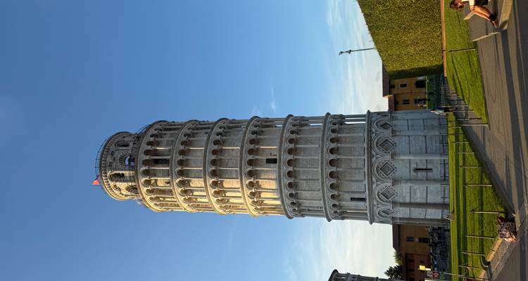 The Leaning Tower of Pisa with people relaxing on the grass.