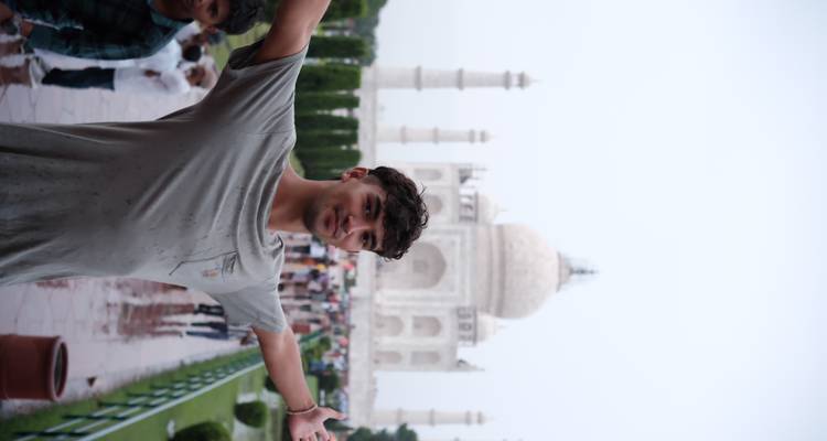 Person in front of the Taj Mahal posing with arms spread.