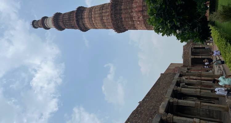Des gens marchant près d'une ancienne structure en pierre et d'un grand minaret.