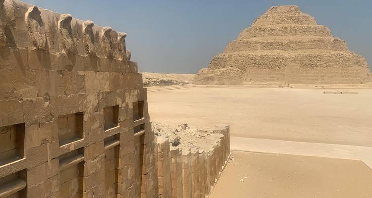Ancient pyramid and an old stone structure in a desert.