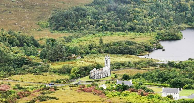 Vue panoramique d'une église historique nichée dans un paysage verdoyant.