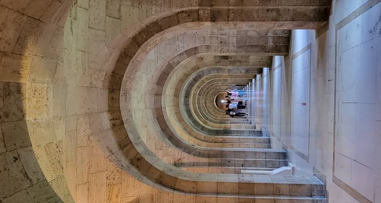 Couloir en béton avec une série d'arcades menant au loin.