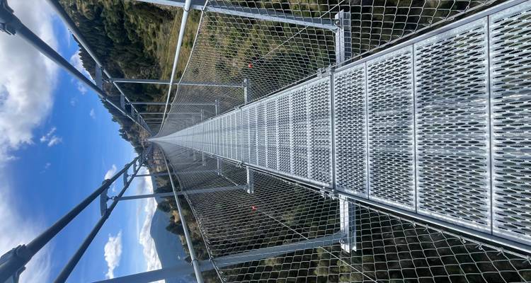 Metallhängebrücke über eine bergige Landschaft.
