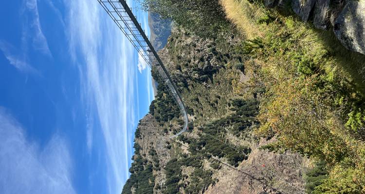 Hängebrücke, die sich über ein Tal mit Hügeln erstreckt.