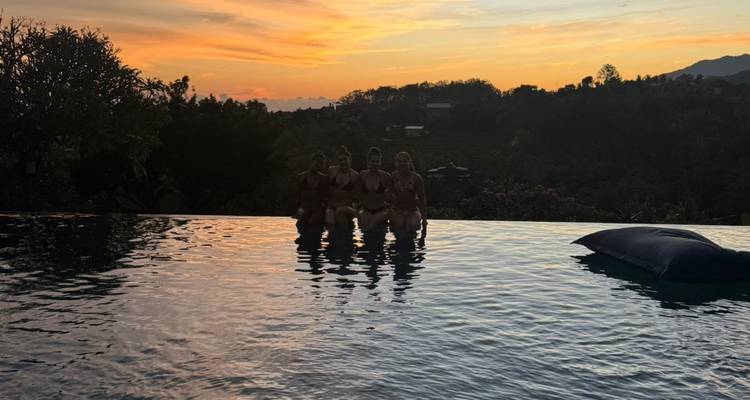 Silhouetted group in an infinity pool at sunset.