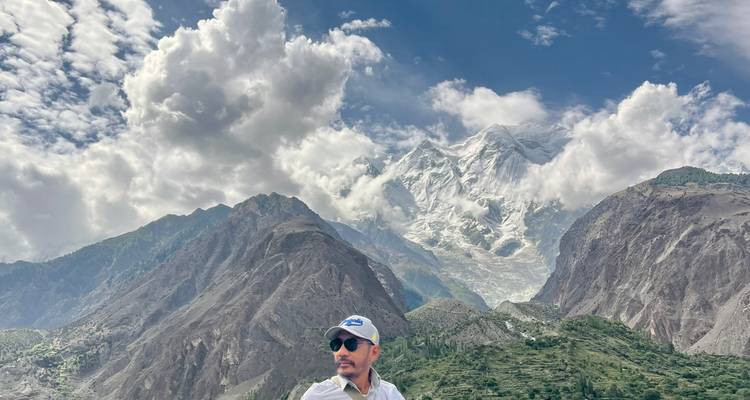 Man standing with a mountainous backdrop in clear weather.