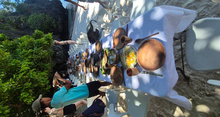 Buiteneetgelegenheid op een strand met witte tafellakens en houten borden.