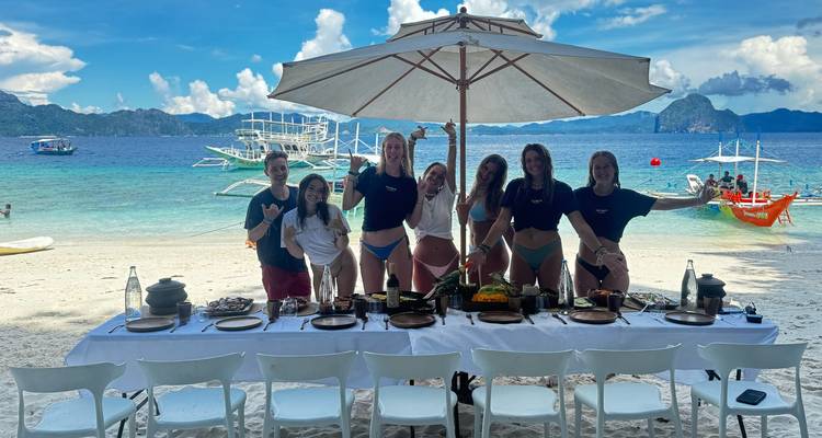 Groupe de personnes posant près d'une table installée sur la plage.