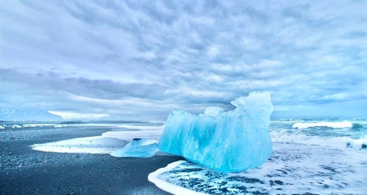 Grande formation de glace échouée sur une plage de sable noir.