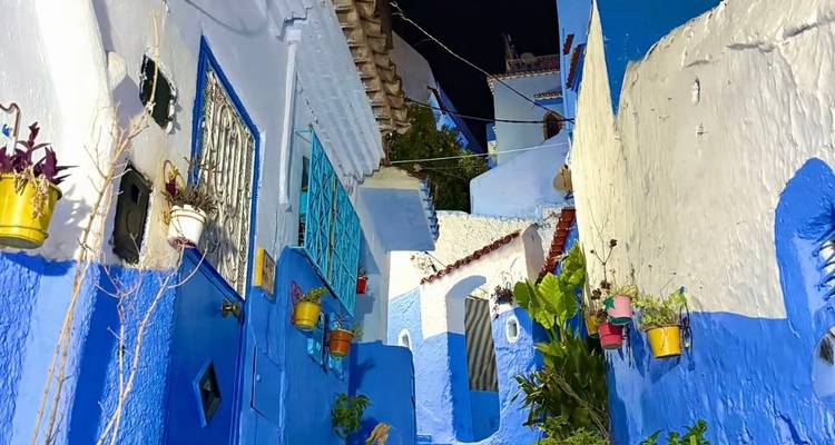 Blue-colored narrow street with traditional Moroccan architecture at night.