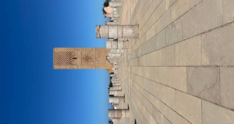 Paved area with Roman ruins and a tall tower in the background.