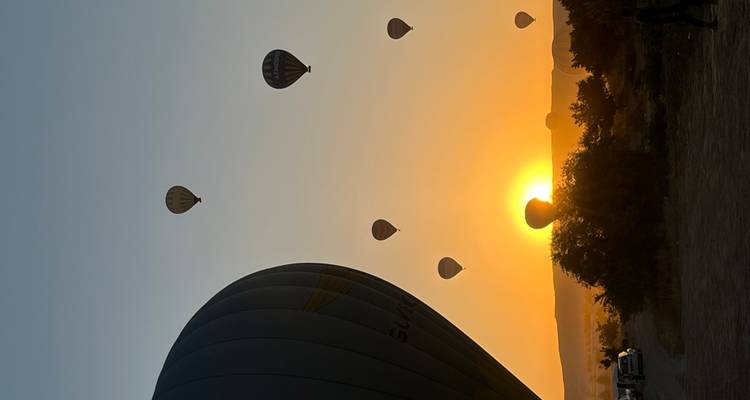 Hot air balloons in the sky against a rising sun.