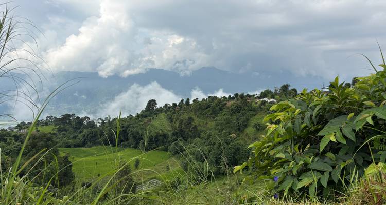 Scenic hillside landscape with clouds and distant mountains