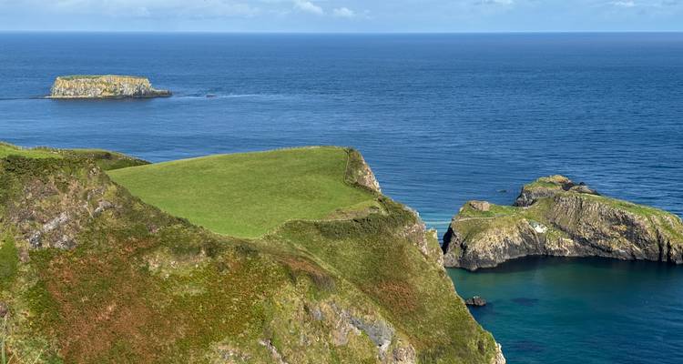 Coastal cliffs with green grass and blue ocean.