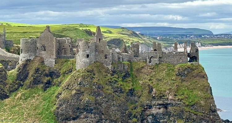 Dunluce Castle ruins on a cliffside with sea in the background.