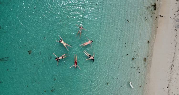 A group of people floating in clear turquoise water viewed from above.