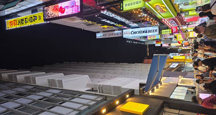 Bustling street at night with bright neon signs and people walking.