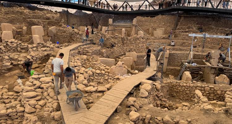 Site archéologique avec des personnes marchant sur des sentiers.