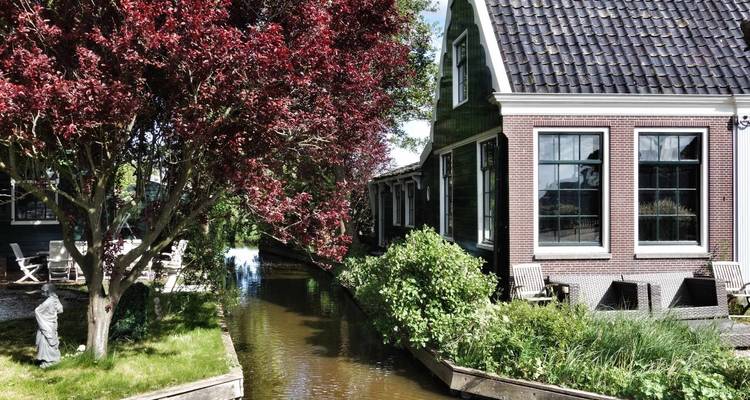 A picturesque canal with houses and lush red foliage.