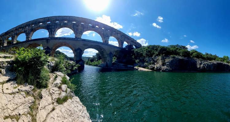 Een historisch aquaduct over een rivier onder een heldere hemel.