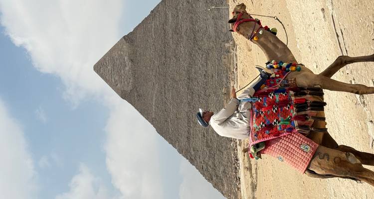 Homme montant un chameau près des pyramides.