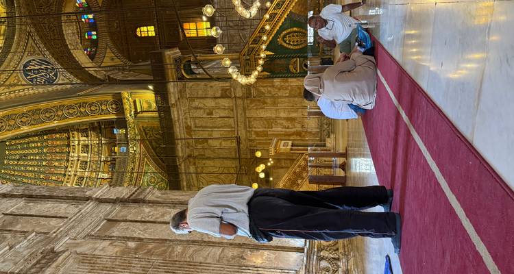 Intérieur d'une mosquée avec des gens assis en train de prier.