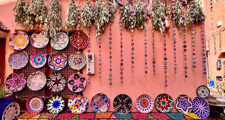 Artistieke weergave van kleurrijke, gepatroneerde handwerkstukken aan een muur.