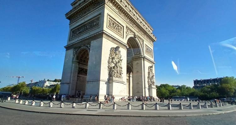 L'Arc de Triomphe à Paris avec une foule et un ciel bleu clair.