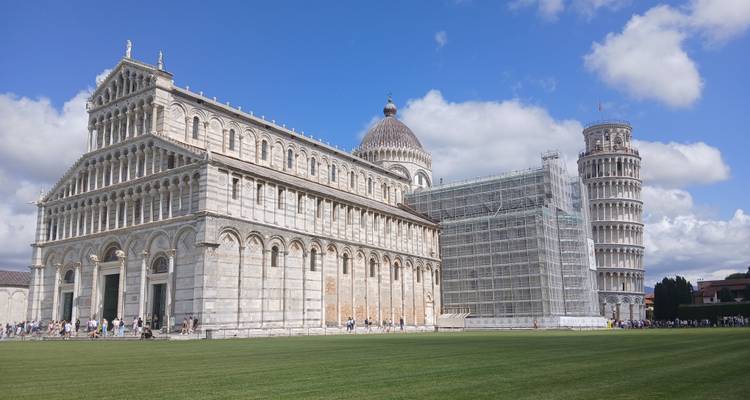 La Tour penchée de Pise avec les bâtiments environnants sous un ciel bleu.