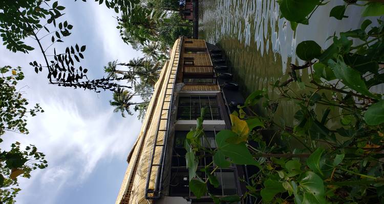 A traditional Indian houseboat on the water surrounded by lush greenery.