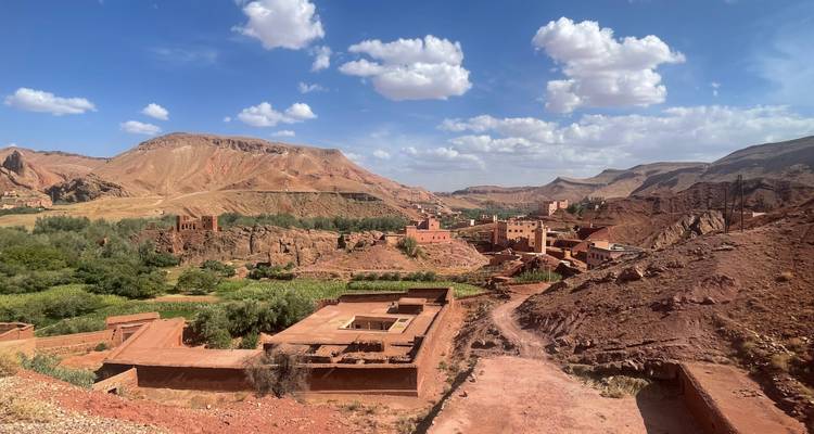 Vue panoramique d'un village avec des bâtiments en argile rouge dans une vallée de montagne.