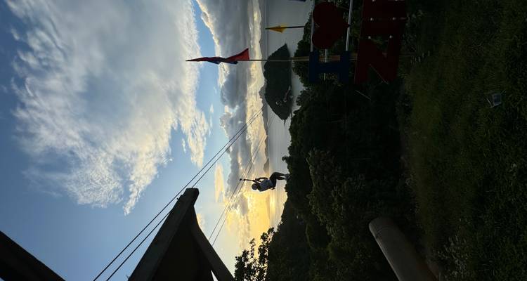 Person zip-lining with ocean view at sunset.