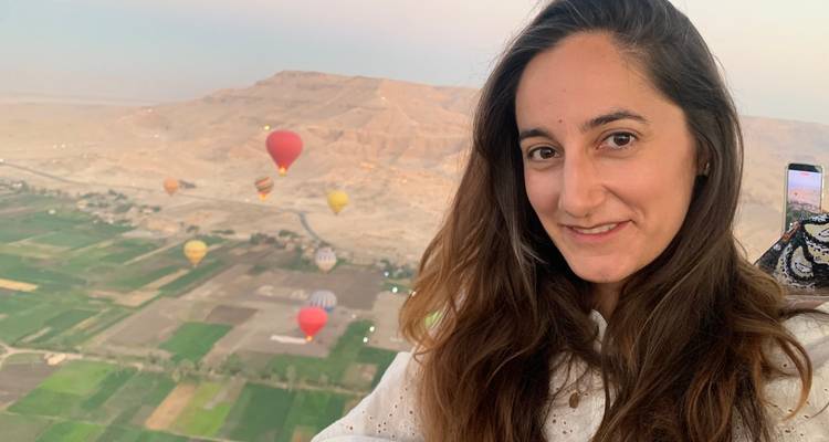 Woman taking a selfie with hot air balloons in the background.