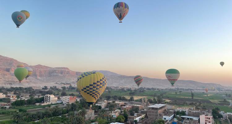 Hot air balloons over a landscape at sunrise.