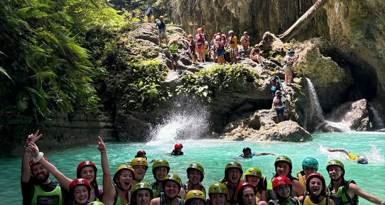 Groupe de personnes nageant près d'une cascade.