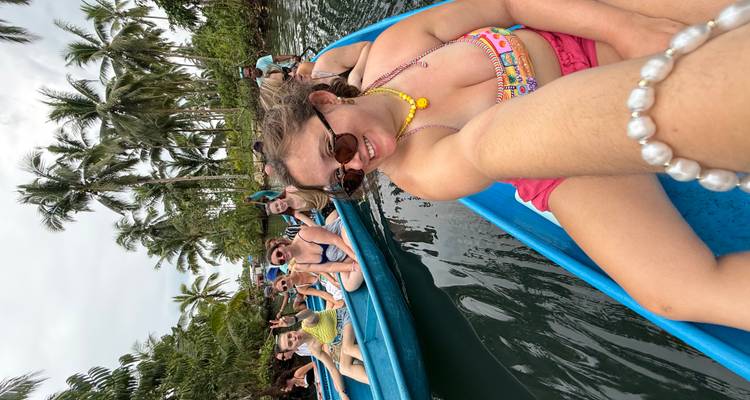 Des gens naviguant en bateau sur une rivière avec des palmiers sur les côtés.
