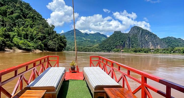 View from a boat on a river with mountains and clear sky.
