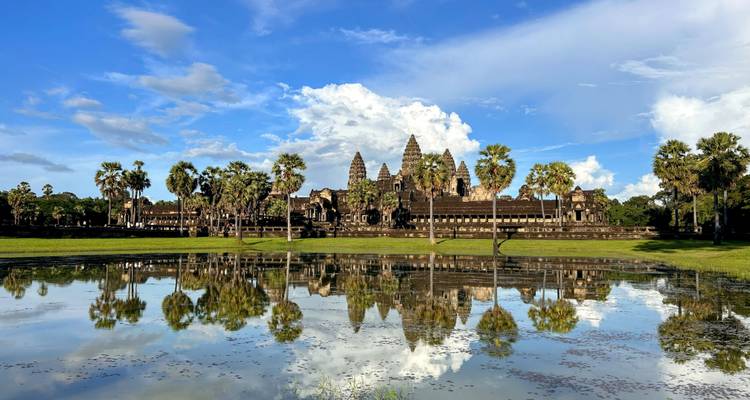 Angkor Wat temple reflecting in water under a vibrant sky.