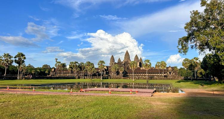 Angkor Wat avec des reflets clairs dans l'eau et un ciel dégagé.