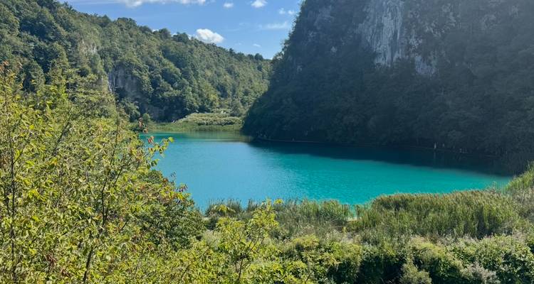 Turquoise lake surrounded by forested hills.